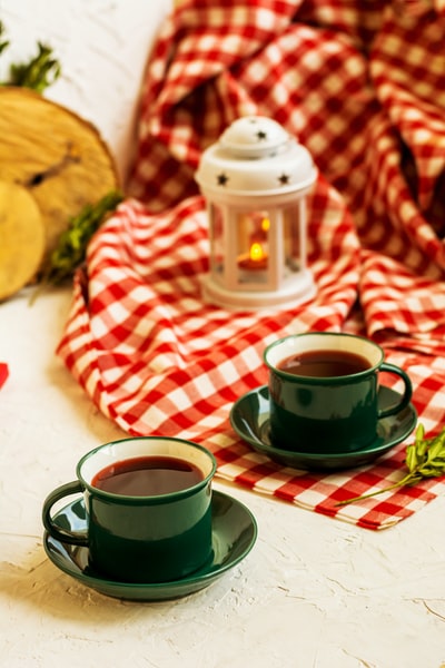 Two and a half full cup of green tea, near the red blanket and desk lamp
